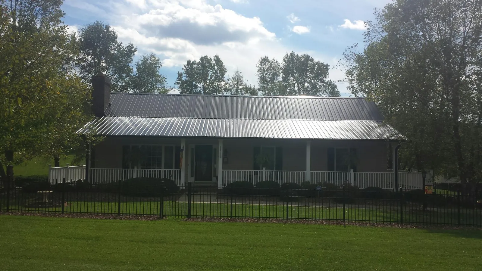Gray metal roof on a brick ranch with a full width front porch — Gutter Guard Installation work by our crew in Fayette